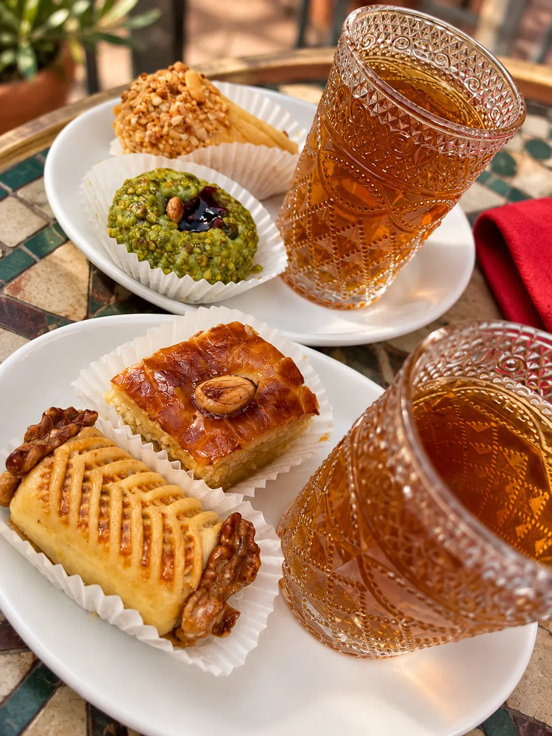 Assortiment de pâtisseries orientales et verres de thé à la menthe sur une table en mosaïque