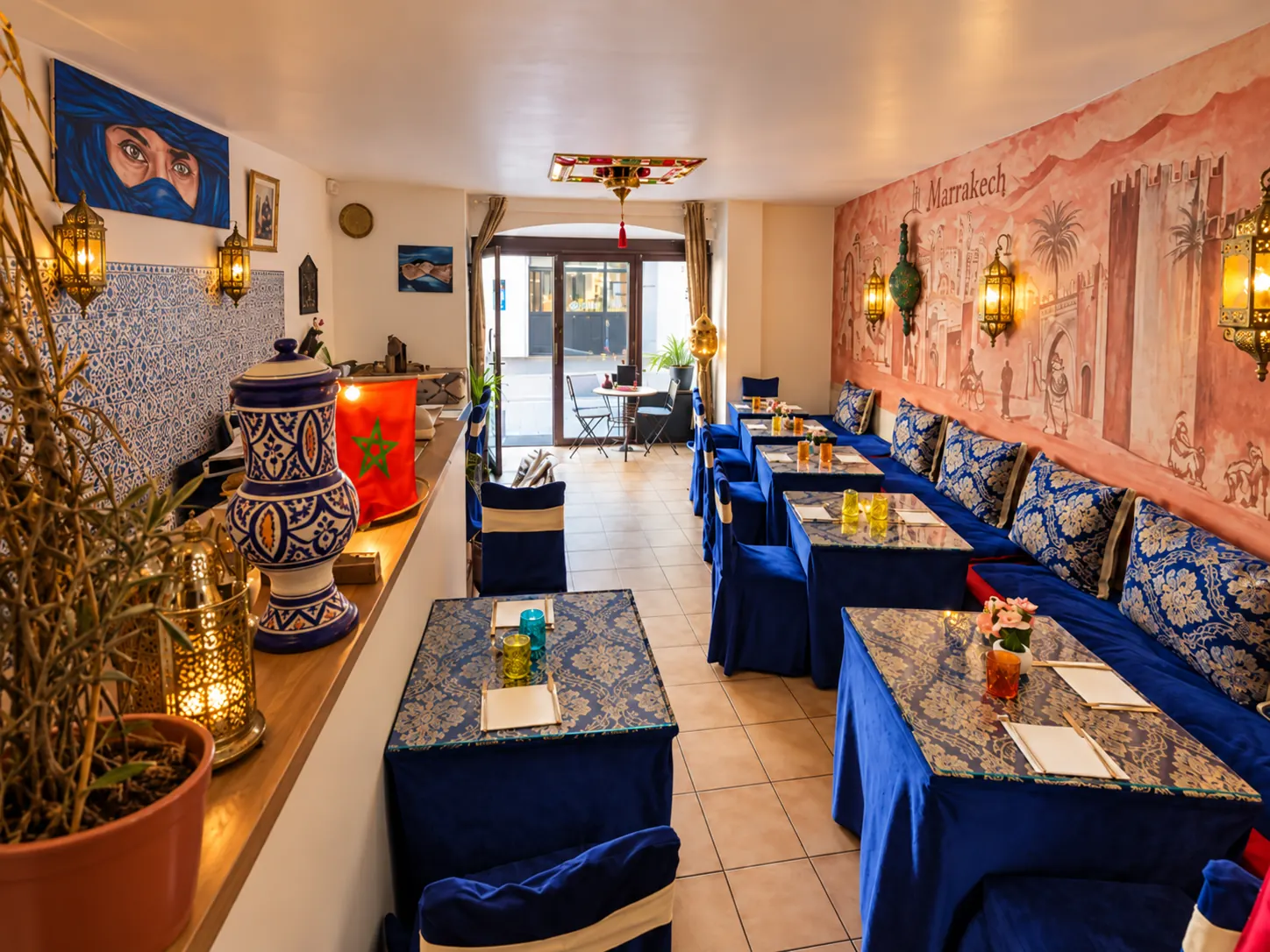 Salle du restaurant Chez Khalid – Le Marrakech à Évian-les-Bains : banquettes bleues, fresque de Marrakech et lanternes marocaines