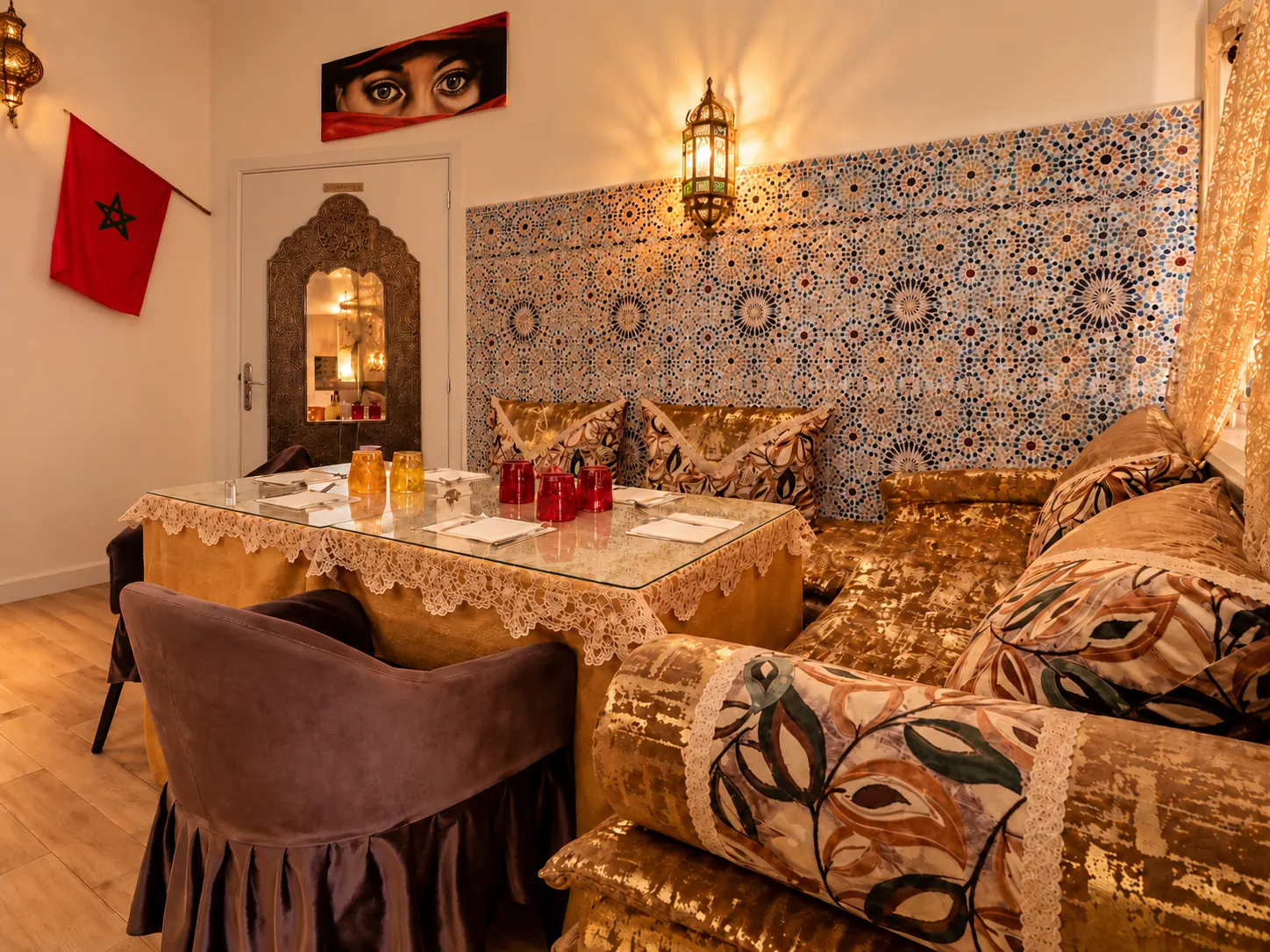 Salon marocain du restaurant : banquette dorée, coussins brodés, zellige et lanterne ciselée