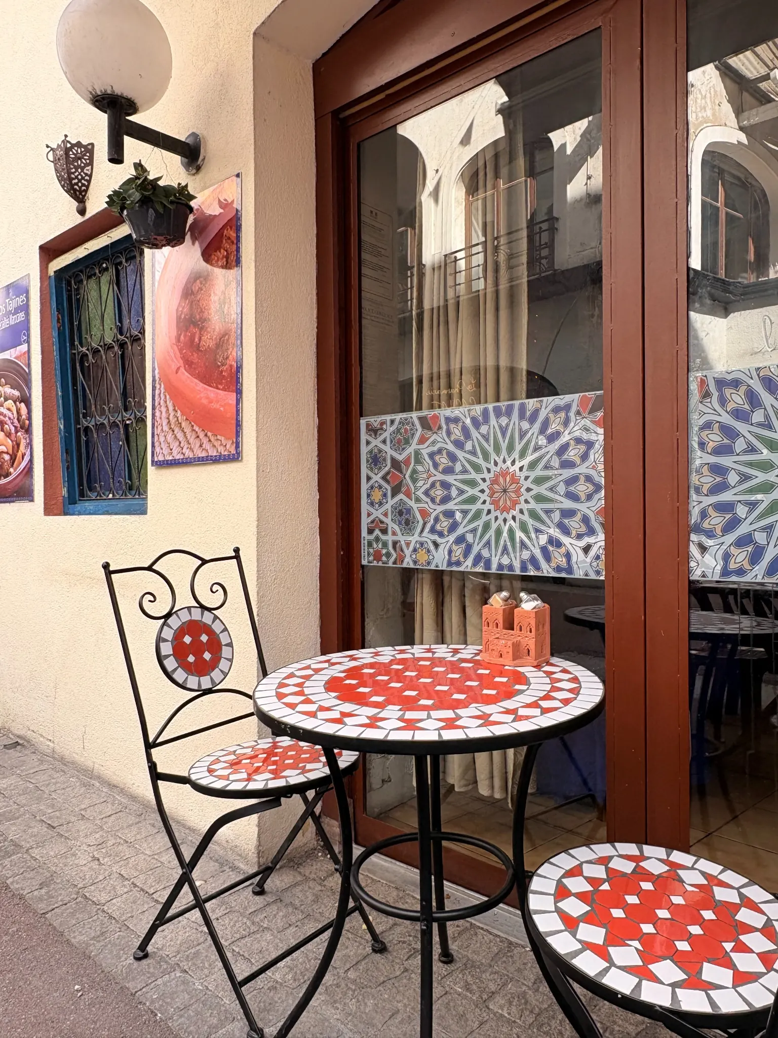 Table en mosaïque rouge et blanche sur la terrasse, devant la façade en zellige
